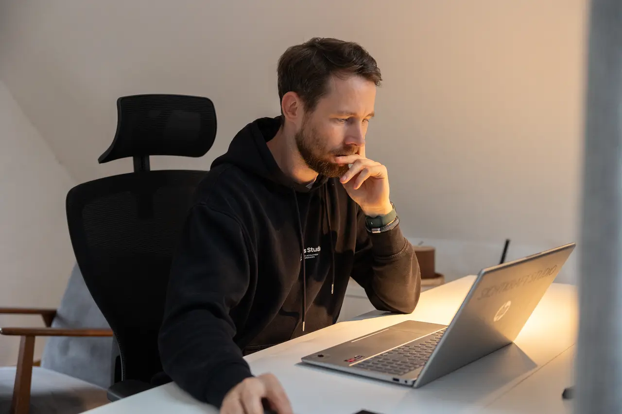 Dirk Grüner sitzt nachdenklich am Schreibtisch und schaut auf den Laptop
